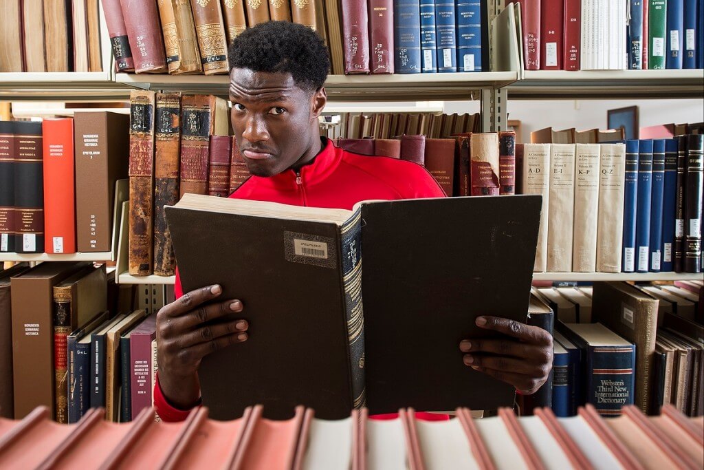 No doubt adding to his already impressive vocabulary, Badger basketball player Nigel Hayes browses books during a photo shoot for a UW-Madison Libraries READ poster.