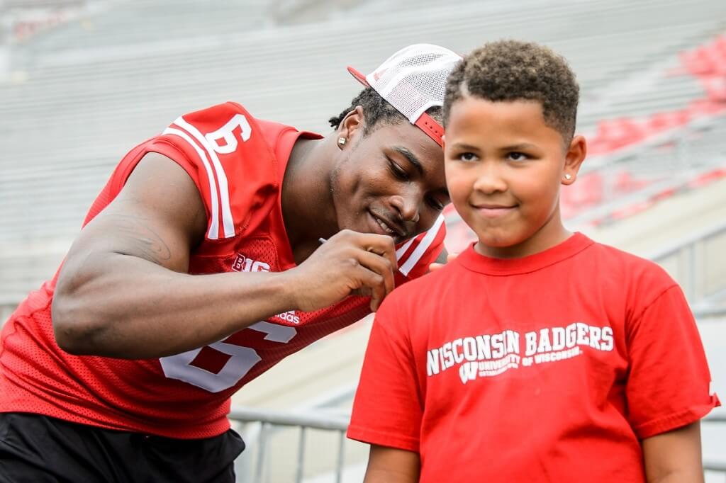 It’s the thrill of this young fan’s life as Badgers running back Corey Clement signs his T-shirt during Family Fun Day at Camp Randall Stadium.