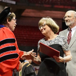 Chancellor Rebecca Blank greets the parents of graduate student Craig Schuff as they received his posthumous degree during Friday's commencement exercises at the Kohl Center. Schuff died in October, months away from completing his Ph.D. in nuclear engineering.