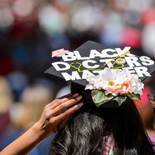 Soon-to-be graduate Morgan Hill adjust her mortarboard – decorated with the message, "Black Doctors Matter" – as she walks toward Camp Randall Stadium at the University of Wisconsin-Madison before the start of UW-Madison's spring commencement ceremony on May 13, 2017. Hill is gradating with a bachelor's degree in Biology with a certificate in global health. The outdoor graduation is expected to be attended by more than 6,000 bachelor's and master's degree candidates, and their guests. (Photo by Jeff Miller/UW-Madison)