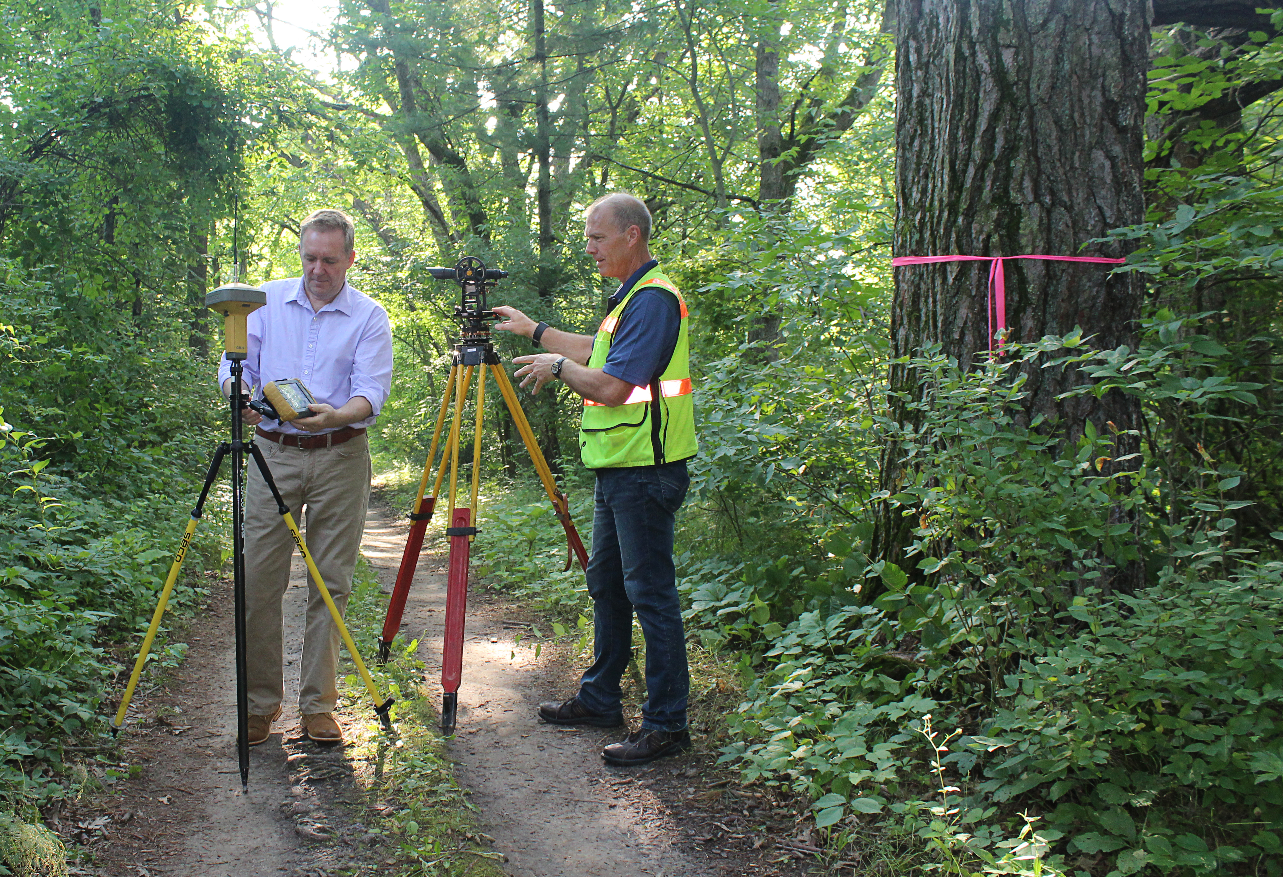 At a location in La Crosse County, state cartographer Howard Veregin, on left, stands next to a modern, GPS-assisted surveying instrument. On right, Bryan Meyers, La Crosse County Surveyor and president of the Wisconsin County Surveyors Association, stands with a transit like the one likely used to survey this site. 
