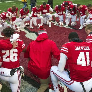 Photo of team members kneeling and praying together after their final home game of the season.