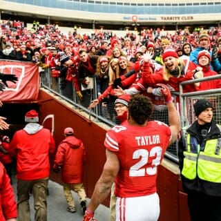 Wisconsin running back Jonathan Taylor (23) waves to cheering Wisconsin Badger fans following Wisconsin's 24-10 football victory over the Michigan Wolverines at Camp Randall Stadium at the University of Wisconsin-Madison on Nov. 18, 2017. (Photo by Jeff Miller / UW-Madison)
