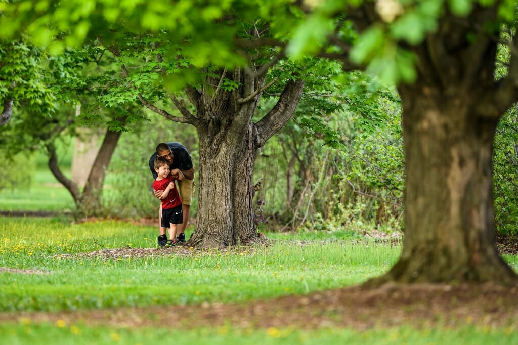 Photo: Family playing hide and seek by a tree