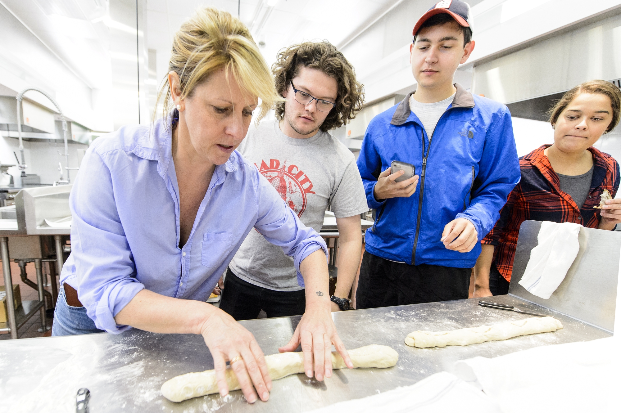 Michelle Clasen (left), of Clasen's Bakery, demonstrates how to roll bread dough to students during a Fermented Food and Beverage class taught by Nick Smith.
