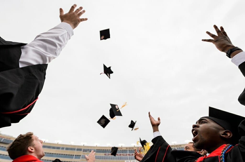 Photo of graduates tossing caps into the air.