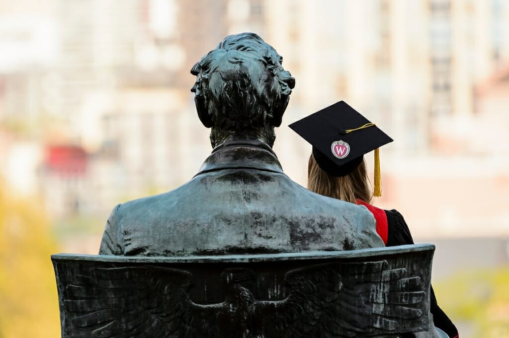 A graduating senior honors the tradition of sitting on the lap of the Abraham Lincoln statue.
