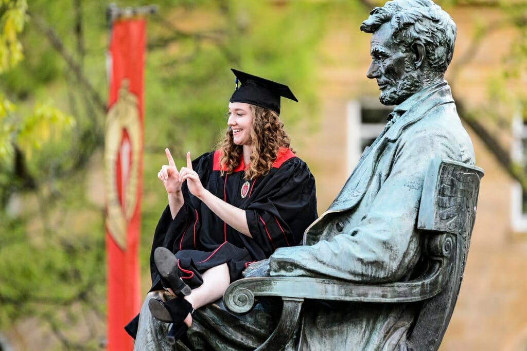 Ellie Schu, graduating with a bachelors in accounting and communications arts, flashes a W from the Abe Lincoln statue.