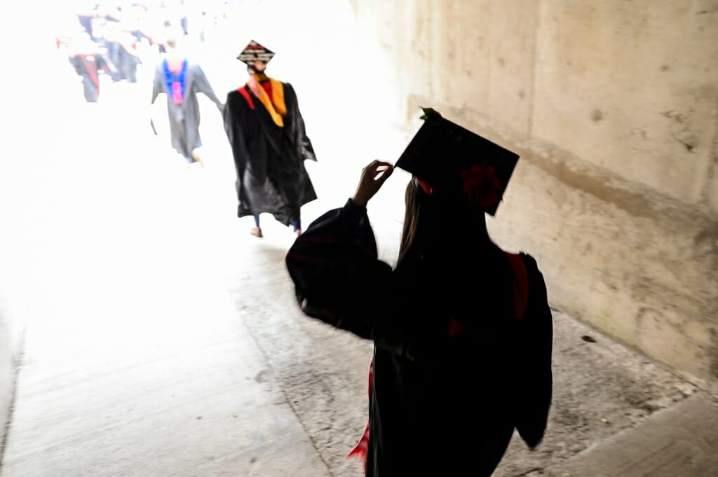 Photo of a graduate adjusting her mortarboard before walking through a tunnel to enter Camp Randall for Saturday's ceremony.