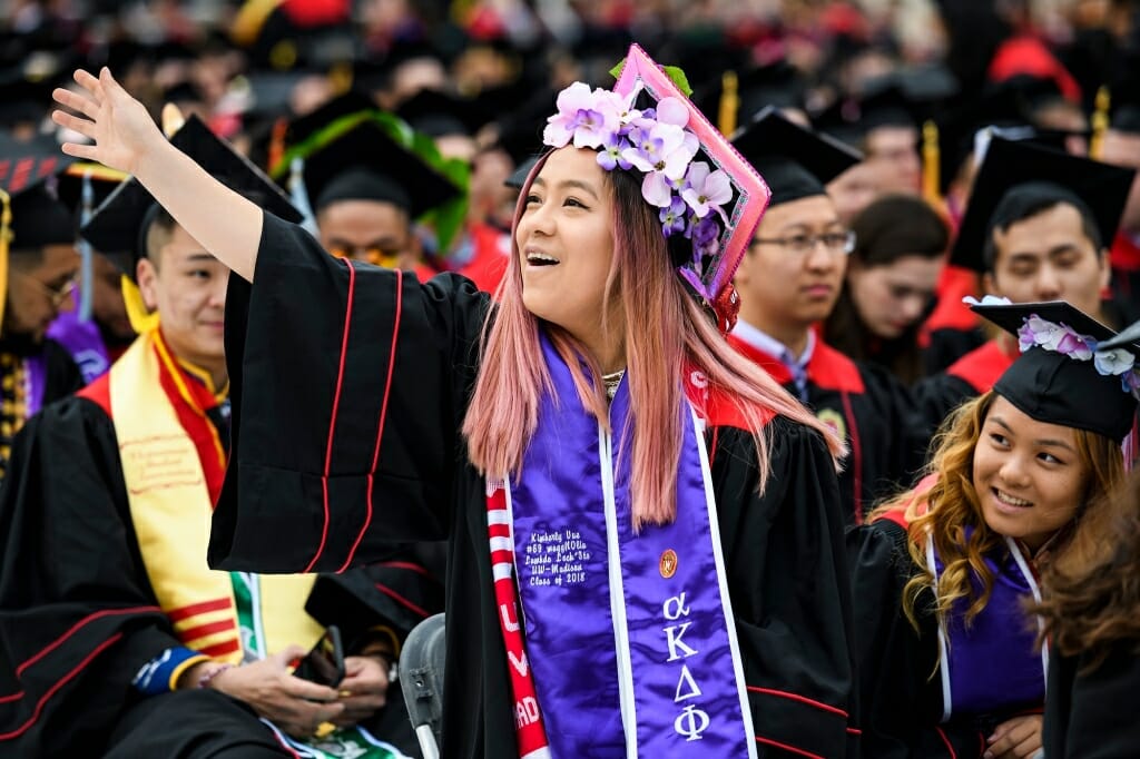 Photo of Kimberly Vue, a first-generation graduate and daughter of Hmong refugees, waving to her family.